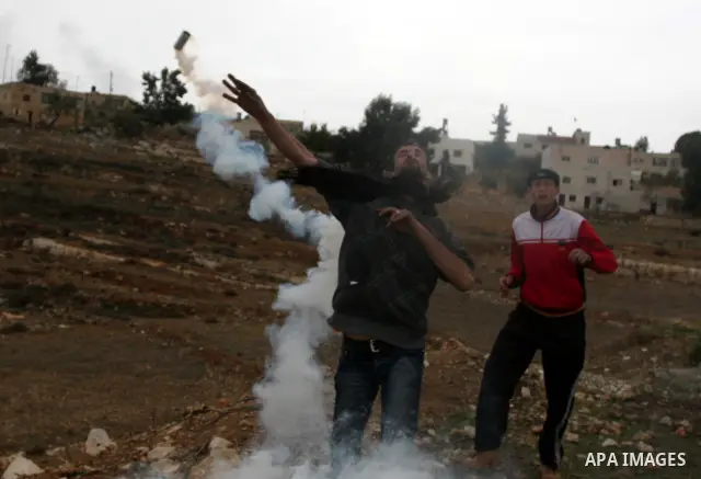 A Palestinian stone-thrower hurl back a tear gas canister fired by Israeli soldiers during clashes at a weekly protest in the West Bank village of Nabi Saleh, near Ramallah November 18, 2011. Photo by Issam Rimawi