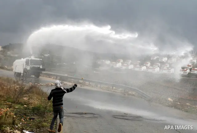 Palestinian youths and Israeli troops clash following a weekly demonstration against Israeli settlement expansion (background), in the West Bank village of Nabi Saleh, on November 18, 2011. Photo by Issam Rimawi