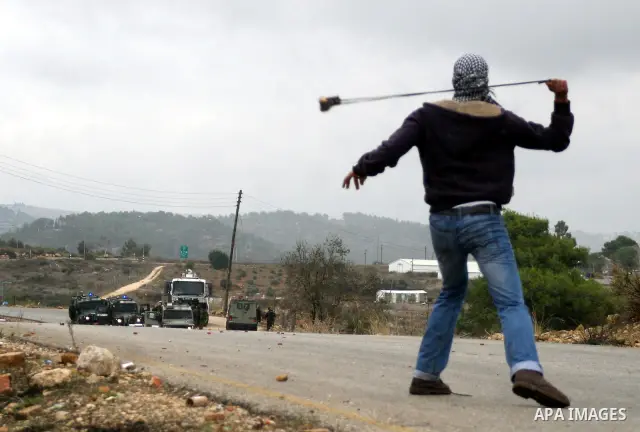 A Palestinian youth uses a sling to throw a stone toward Israeli soldiers during clashes at a weekly protest in the West Bank village of Nabi Saleh, near Ramallah November 18, 2011. Photo by Issam Rimawi