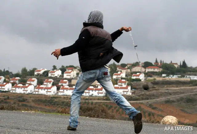 A Palestinian youth uses a sling to throw a stone toward Israeli soldiers during clashes at a weekly protest in the West Bank village of Nabi Saleh, near Ramallah November 18, 2011. Photo by Issam Rimawi