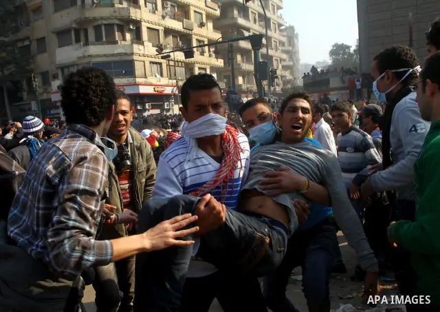 Protesters help another protester injured during clashes with riot police near Tahrir square in Cairo, Egypt, Wednesday, Nov. 23, 2011. Egyptian police are clashing with anti-government protesters for a fifth day in Cair...