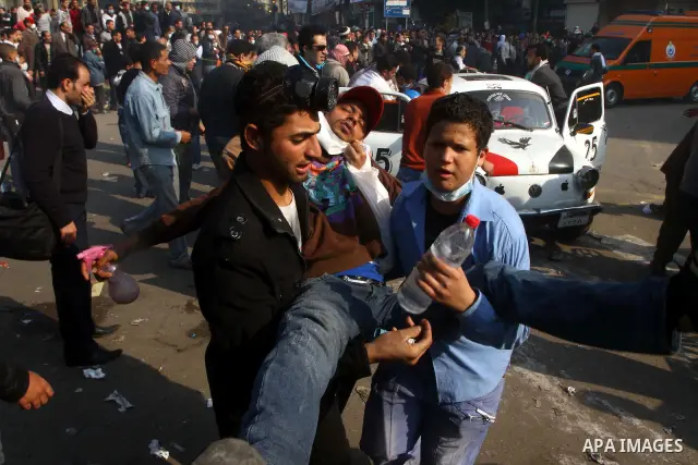 Protesters help another protester injured during clashes with riot police near Tahrir square in Cairo, Egypt, Wednesday, Nov. 23, 2011. Egyptian police are clashing with anti-government protesters for a fifth day in Cair...
