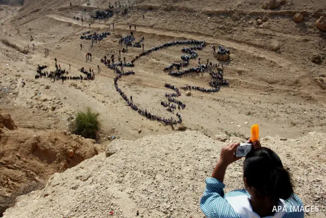 Palestinian children stand to form Pablo Picasso's Dove of Peace as part of a project by British aerial artist John Quigley and the United Nations Relief Works Agency (UNRWA), at the foot of the Mount of Temptation in th...