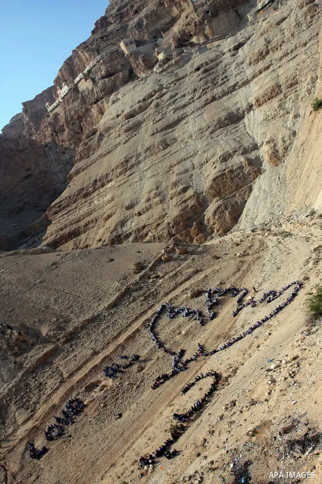 Palestinian children stand to form Pablo Picasso's Dove of Peace as part of a project by British aerial artist John Quigley and the United Nations Relief Works Agency (UNRWA), at the foot of the Mount of Temptation in th...