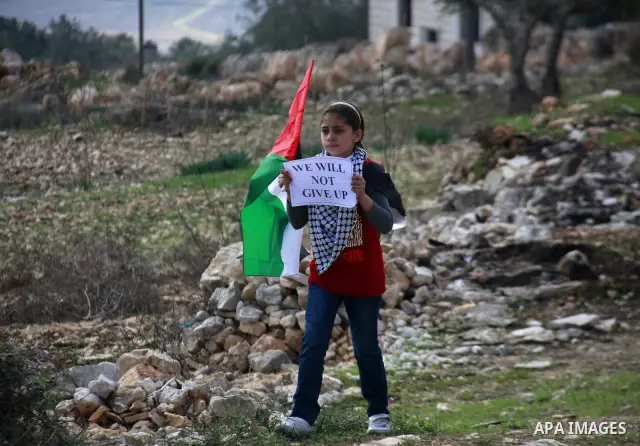 A Palestinian girl holds a banner during a protest near Kufr Qaddum, near the northern West Bank Jewish settlement of Kdumim Friday, Nov. 25, 2011. The protest was held against the closure of a main road in the village....