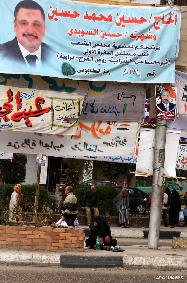 Egyptians walk past electoral campaign banners in Cairo on November 26, 2011 ahead of a three-round parliamentary election. The parliamentary elections that get underway on November 28 will be the first polls since a pop...