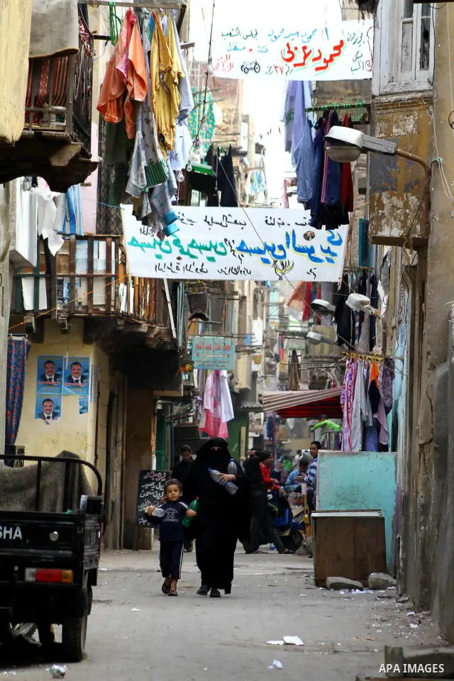 Egyptians walk past electoral campaign banners in Cairo on November 26, 2011 ahead of a three-round parliamentary election. The parliamentary elections that get underway on November 28 will be the first polls since a pop...