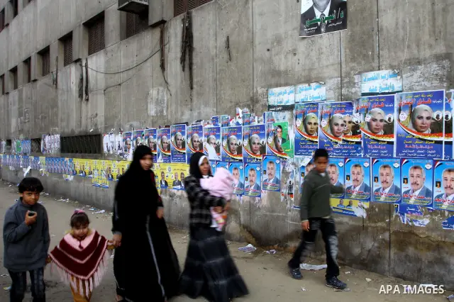 Egyptians walk past electoral campaign posters and banners for candidates in Cairo on November 27, 2011 on the eve of the first parliament elections since the end of the 30-year rule of strongman Hosni Mubarak. Photo by...