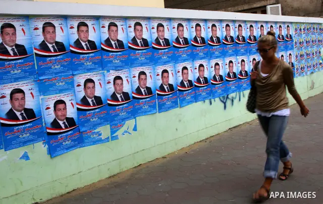 A foreign woman walks past electoral campaign posters and banners for candidates in Cairo on November 27, 2011 on the eve of the first parliament elections since the end of the 30-year rule of strongman Hosni Mubarak. Ph...