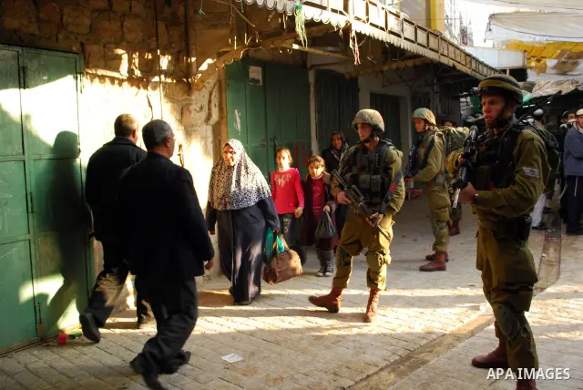 Israeli soldiers block a narrow street in the old quarter of the Israeli occupied West Bank city of Hebron, on November 26, 2011, to allow Jewish settlers and other Israelis to tour the Palestinian area of the old city a...