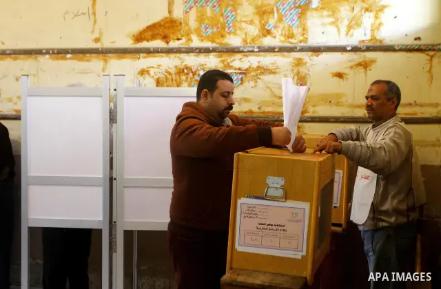 Elections staff members hel voters to determine their number during the vote in the first round of Egypt's parliamentary elections at a polling station in Cairo during the first round of Egypt's Parliamentary elections a...