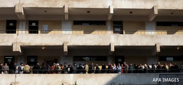 Voters line up inside a polling center beneath campaign posters on the first day of parliamentary elections in Cairo, Egypt, Monday, Nov. 28, 2011. Shaking off years of political apathy, Egyptians on Monday began voting...