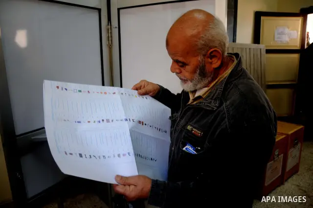 Egyptian man read voting materials at a polling center in Cairo, Egypt, Monday, Nov. 28, 2011.Voting began on Monday in Egypt's first parliamentary elections since longtime authoritarian leader Hosni Mubarak was ousted i...