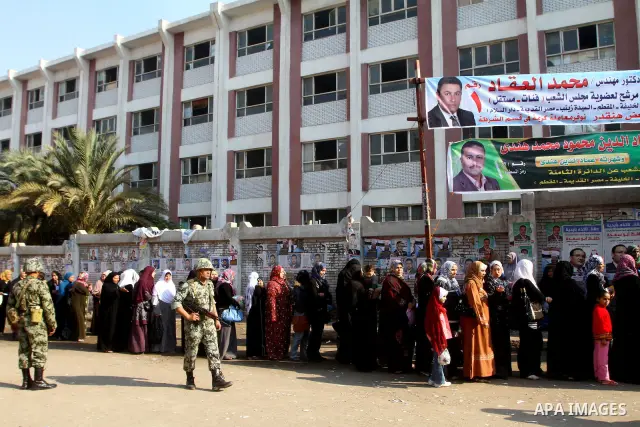 Army soldier stands guard as Egyptians wait in line to vote at a polling station in the Moqattam district of Cairo on November 29, 2011. Egypt hailed the start of its first post-revolution election as a triumph for democ...