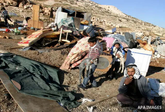 Palestinian Bedouin children collect belongings amidst the rubble of a structure after it was razed by the Israeli army in the West Bank village of Zayem, near Jerusalem November 29, 2011. According to Israeli authoritie...