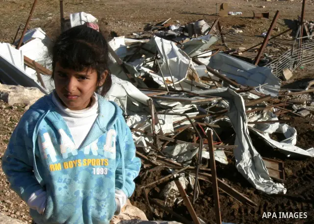 Palestinian Bedouin children collect belongings amidst the rubble of a structure after it was razed by the Israeli army in the West Bank village of Zayem, near Jerusalem November 29, 2011. According to Israeli authoritie...
