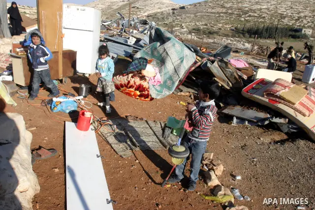 Palestinian Bedouin children collect belongings amidst the rubble of a structure after it was razed by the Israeli army in the West Bank village of Zayem, near Jerusalem November 29, 2011. According to Israeli authoritie...