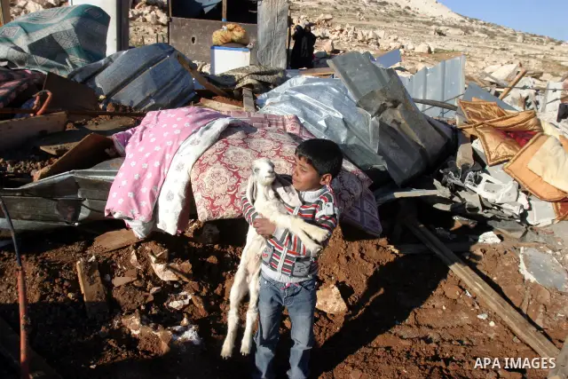 Palestinian Bedouin children collect belongings amidst the rubble of a structure after it was razed by the Israeli army in the West Bank village of Zayem, near Jerusalem November 29, 2011. According to Israeli authoritie...