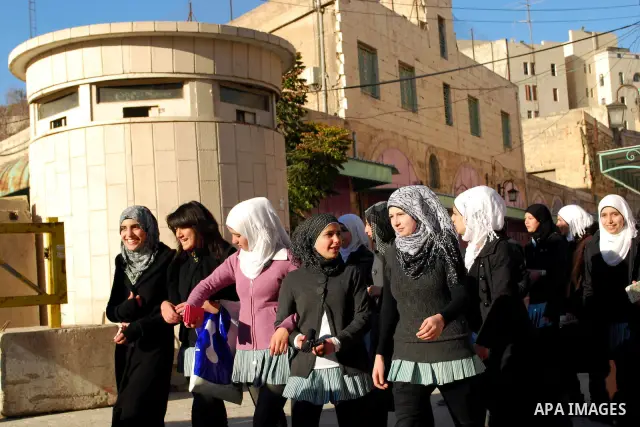 Palestinian schoolgirls walk past an Israeli checkpoint during their visit to the Ibrahimi mosque or the "Tomb of Patriarch" in the old city of Hebron on Dec. 1,2011. Photo by Osama Qawasmi