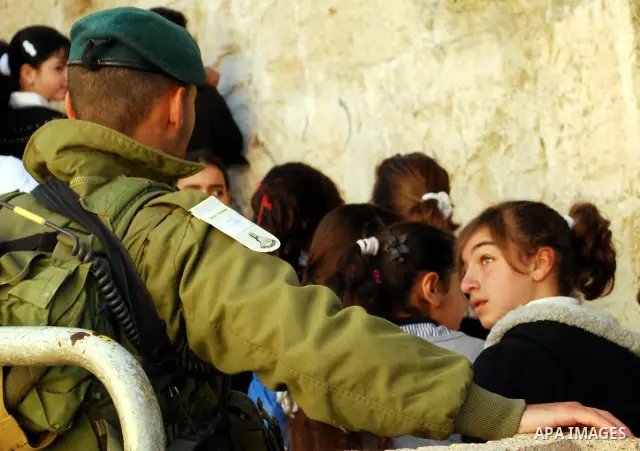 Palestinian schoolgirls walk past an Israeli checkpoint during their visit to the Ibrahimi mosque or the "Tomb of Patriarch" in the old city of Hebron on Dec. 1,2011. Photo by Osama Qawasmi