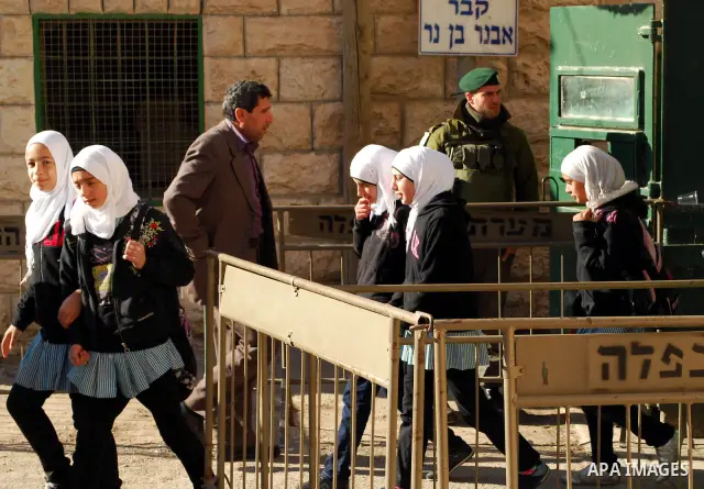 Palestinian schoolgirls walk past an Israeli checkpoint during their visit to the Ibrahimi mosque or the "Tomb of Patriarch" in the old city of Hebron on Dec. 1,2011. Photo by Osama Qawasmi