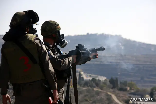 Israeli border police officers fire tear gas towards Palestinian demonstrators, not seen, during a protest in the village of Kufr Qaddum near the Israeli settlement of Kdumim, in the northern West Bank, Friday, Dec. 2, 2...