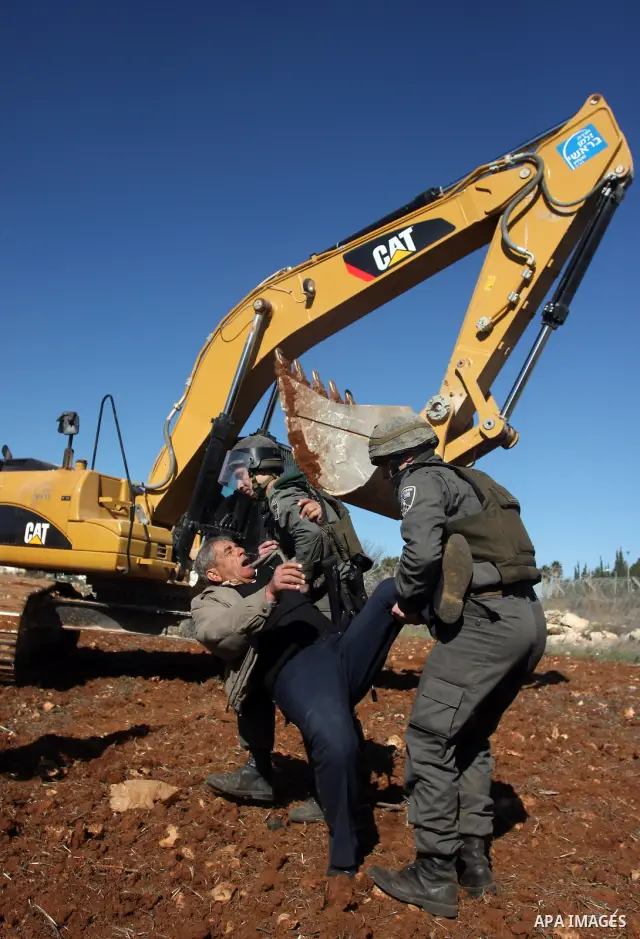 A Palestinian man is carried by Israeli border police officers after he tried to block a construction vehicle from working on Israel's barrier in the West Bank village of Qaladiya near Ramallah December 4, 2011. Accordin...