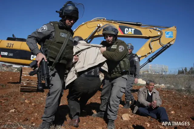 A Palestinian man is carried by Israeli border police officers after he tried to block a construction vehicle from working on Israel's barrier in the West Bank village of Qaladiya near Ramallah December 4, 2011. Accordin...