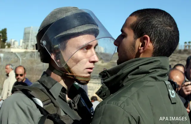 Israeli border police officers scuffle with a Palestinian man after he tried to block a construction vehicle from working on Israel's barrier in the West Bank village of Qaladiya near Ramallah December 4, 2011. According...