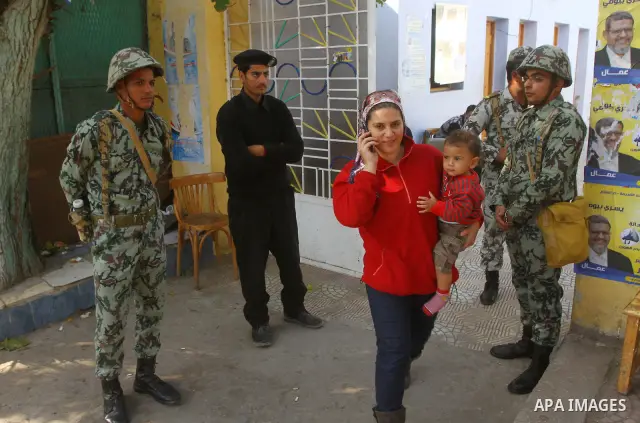 A woman enters a polling station guarded by soldiers and police during the first round of Egypt's run-off parliamentary elections in Cairo December 5, 2011. Egyptians voted on Monday in run-off contests for parliamentary...