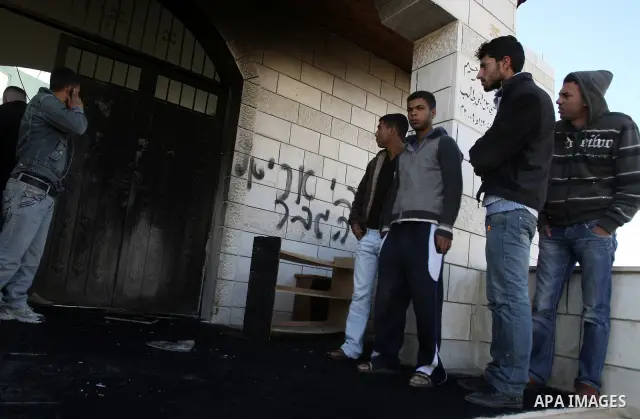 Palestinians stand outside a vandalized mosque where graffiti reading In Hebrew. was sprayed at the entrance of the mosque , in the West Bank Village of Brukin near Nablus, Wednesday , Dec. 07, 2011. Assailants vandalize...