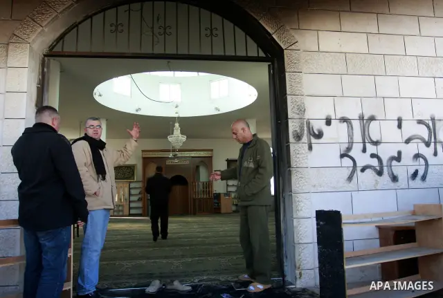 Palestinians stand outside a vandalized mosque where graffiti reading In Hebrew. was sprayed at the entrance of the mosque , in the West Bank Village of Brukin near Nablus, Wednesday , Dec. 07, 2011. Assailants vandalize...