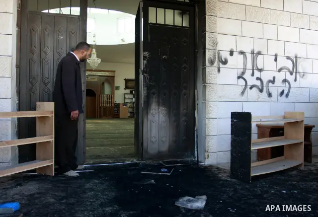Palestinians stand outside a vandalized mosque where graffiti reading In Hebrew. was sprayed at the entrance of the mosque , in the West Bank Village of Brukin near Nablus, Wednesday , Dec. 07, 2011. Assailants vandalize...