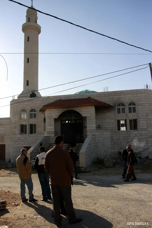 Palestinians stand outside a vandalized mosque where graffiti reading In Hebrew. was sprayed at the entrance of the mosque , in the West Bank Village of Brukin near Nablus, Wednesday , Dec. 07, 2011. Assailants vandalize...