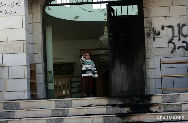 Palestinians stand outside a vandalized mosque where graffiti reading In Hebrew. was sprayed at the entrance of the mosque , in the West Bank Village of Brukin near Nablus, Wednesday , Dec. 07, 2011. Assailants vandalize...