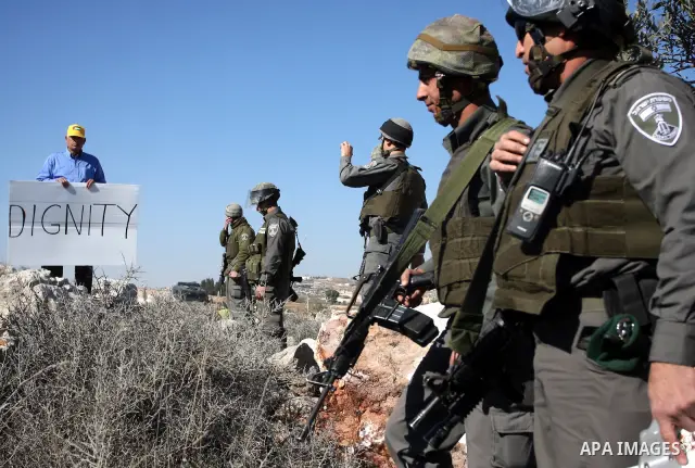 Israeli border police officers scuffle with protesters after they tried to block a construction vehicle from working on Israel's barrier in the West Bank village of Qalandiya near Ramallah December 7, 2011. According to...