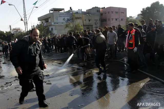 Palestinians crowd around the remains of a car hit by an Israeli air strike in Gaza City December 8, 2011. An Israeli air strike on the car killed at least two Hamas militants and wounded two others on a crowded Gaza str...