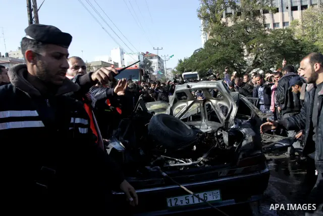 Palestinians crowd around the remains of a car hit by an Israeli air strike in Gaza City December 8, 2011. An Israeli air strike on the car killed at least two Hamas militants and wounded two others on a crowded Gaza str...