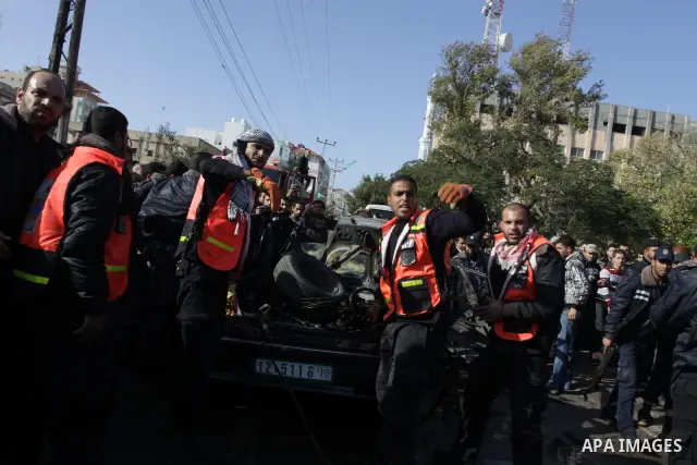 Palestinians crowd around the remains of a car hit by an Israeli air strike in Gaza City December 8, 2011. An Israeli air strike on the car killed at least two Hamas militants and wounded two others on a crowded Gaza str...