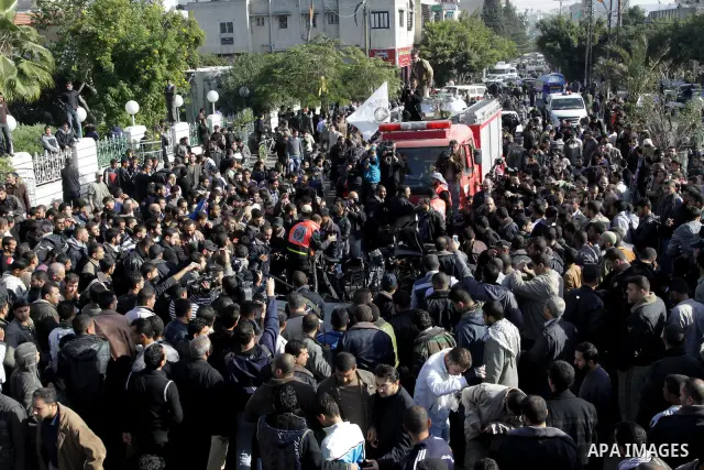 Palestinians crowd around the remains of a car hit by an Israeli air strike in Gaza City December 8, 2011. An Israeli air strike on the car killed at least two Hamas militants and wounded two others on a crowded Gaza str...