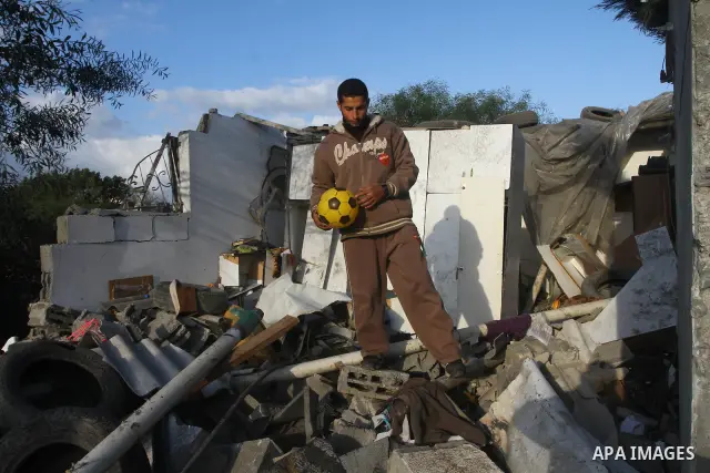 A Palestinian man holds toys as he looks at a house damaged in an Israeli air strike in Gaza City, on December 9, 2011. Violence across the Israeli-Gaza border escalated on Friday with Israeli air strikes killing at leas...