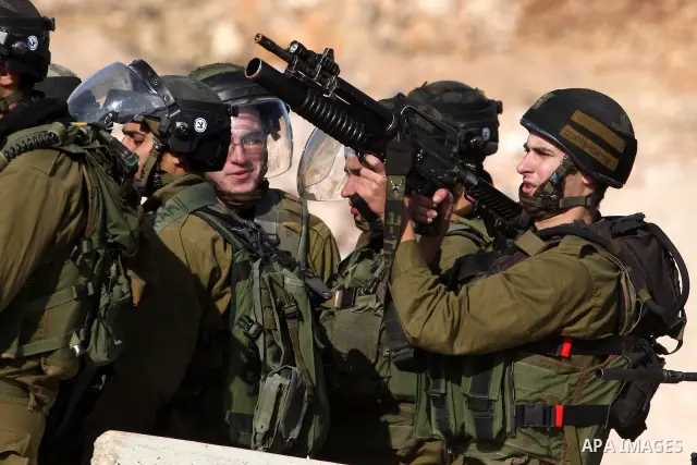 Israeli soldiers fire tear gas at Palestinian demonstrators during a protest against the construction of Israel's separation barrier in the West Bank village of Qalandia, near Ramallah, on December 9, 2011. Photo by Issa...