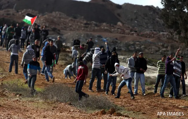 Palestinian demonstrators hurl stones towards Israeli soldiers during a protest against the construction of Israel's separation barrier in the West Bank village of Qalandia, near Ramallah, on December 9, 2011. Photo by I...