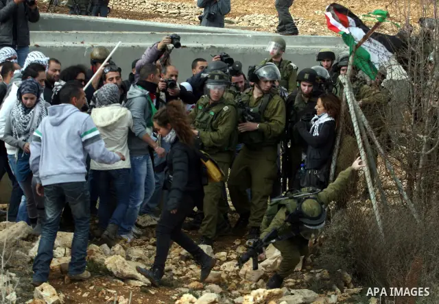 Palestinian and foreign activists argue with Israeli soldiers during a protest against the construction of Israel's separation barrier in the West Bank village of Qalandia, near Ramallah, on December 9, 2011. Photo by Is...