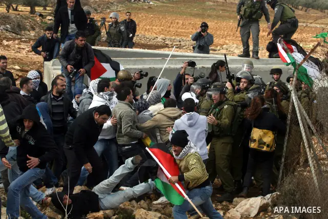 Palestinian and foreign activists argue with Israeli soldiers during a protest against the construction of Israel's separation barrier in the West Bank village of Qalandia, near Ramallah, on December 9, 2011. Photo by Is...