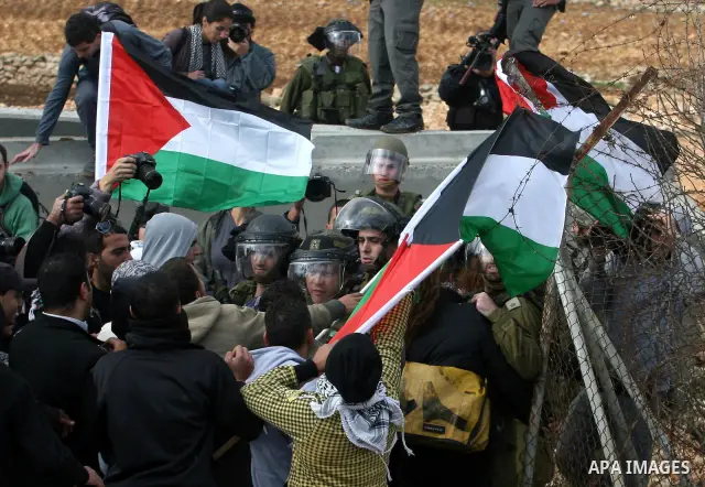 Palestinian and foreign activists argue with Israeli soldiers during a protest against the construction of Israel's separation barrier in the West Bank village of Qalandia, near Ramallah, on December 9, 2011. Photo by Is...