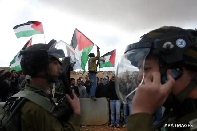Palestinian demonstrators wave their national flag during a protest against the construction of Israel's separation barrier in the West Bank village of Qalandia, near Ramallah, on December 9, 2011. Photo by Issam Rimawi