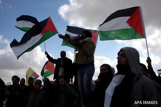 Palestinian demonstrators wave their national flag during a protest against the construction of Israel's separation barrier in the West Bank village of Qalandia, near Ramallah, on December 9, 2011. Photo by Issam Rimawi