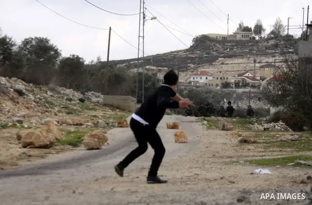 Palestinian protesters throw stones towards Israeli soldiers during clashes that broke out at a weekly demonstration against Israeli-occupation in the northern West Bank village of Kfar Kadum on December 9, 2011. A Pales...