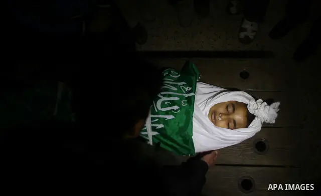 The body of Palestinian boy Ramadan al-Zaalan, 12, lies near mourners during his funeral in Gaza City on December 10, 2011. Zaalan was killed with his father Bahjat in an Israeli air strike on a civilian house in Gaza, m...